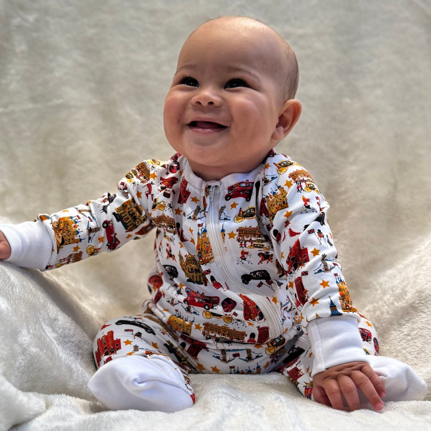 Smiling baby wearing Peckish Goose London Organic Baby Sleepsuit